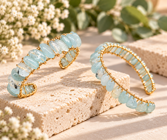 Aquamarine wire wrapped cuff bracelet displayed on natural stone with soft botanical accents